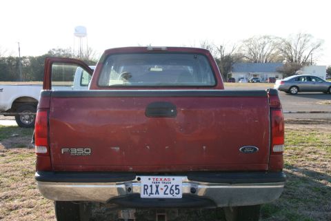1993 Ford Bronco - Rear view of a red Ford F-350 Super Duty pickup truck with an open driver's door and a Texas license plate.