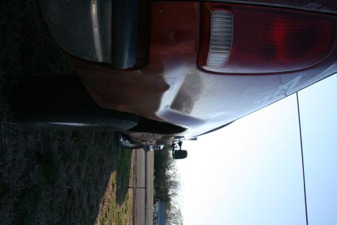 1993 Ford Bronco - The rear quarter panel of a pickup truck shows damage and a red taillight.