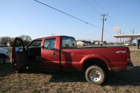 1993 Ford Bronco - This red pickup truck features a 4x4 decal on the rear quarter panel and the driver's door is open.