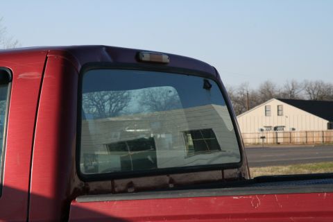 1993 Ford Bronco - Rear view of a 1993 Ford Bronco, highlighting the rear window and a dent on the roof.