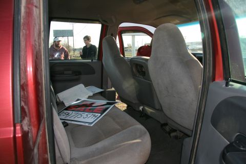 1993 Ford Bronco - Interior view of a red truck with a "FOR SALE" sign and two men outside.