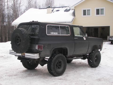 1990 Chevrolet Suburban - This black SUV, likely from the 1980s, is equipped with off-road tires and a spare tire carrier.