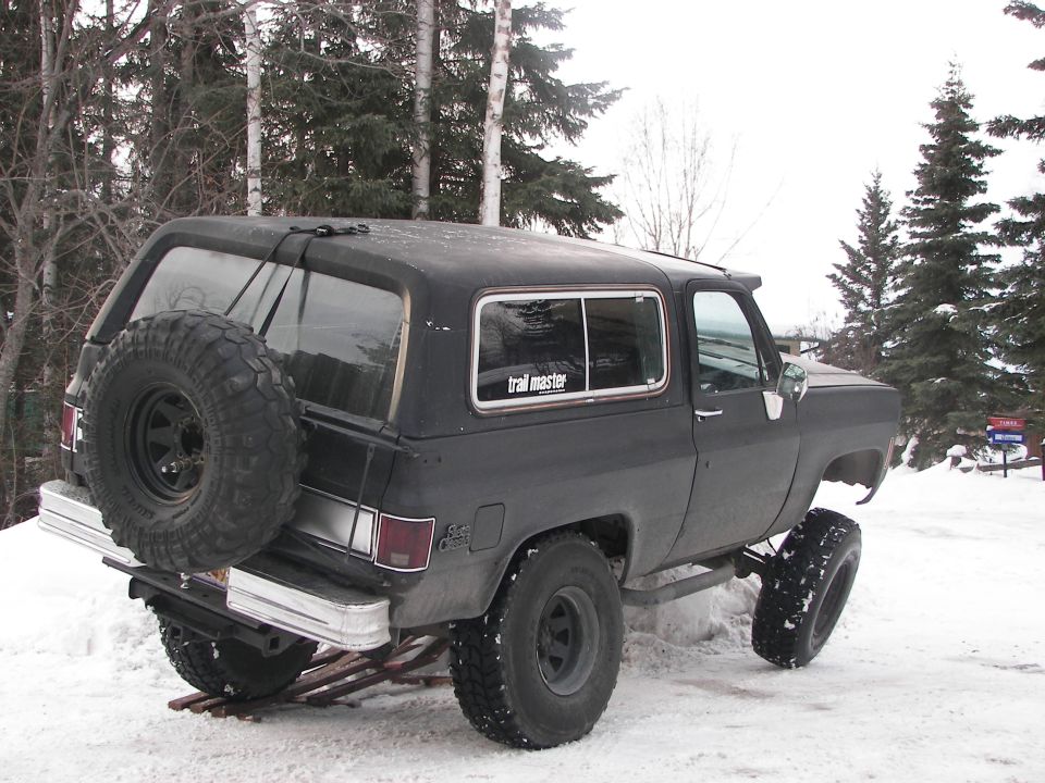 Lifted black Chevrolet K5 Blazer in snow, spare tire mounted on rear carrier