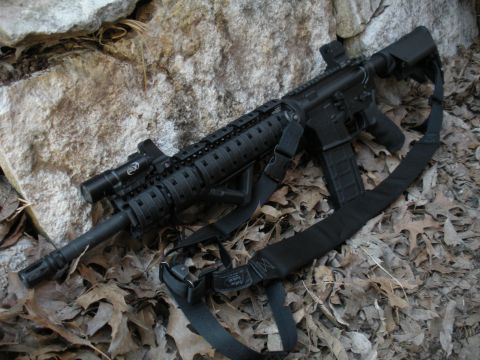 1996 Ford Bronco - A tactical rifle with a sling and mounted light is displayed outdoors on a bed of fallen leaves and rocks.