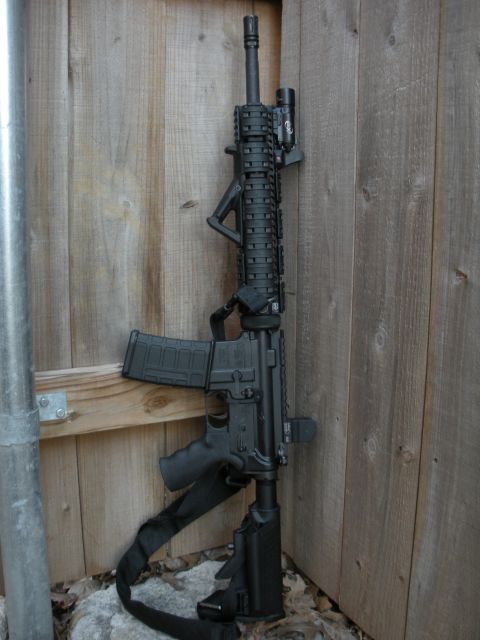 1996 Ford Bronco - AR-15 style rifle with accessories leaning against a wooden fence.