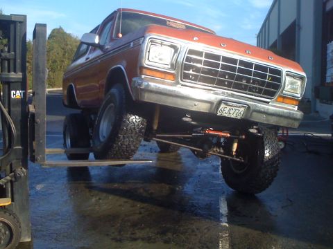 1978 Ford Bronco - Forklift lifts a modified 1978 Ford Bronco with custom suspension and large tires.