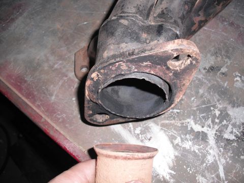 1991 Ford Bronco - A close-up view shows a worn exhaust pipe flange and a separate pipe fitting, likely for a vehicle's exhaust system.