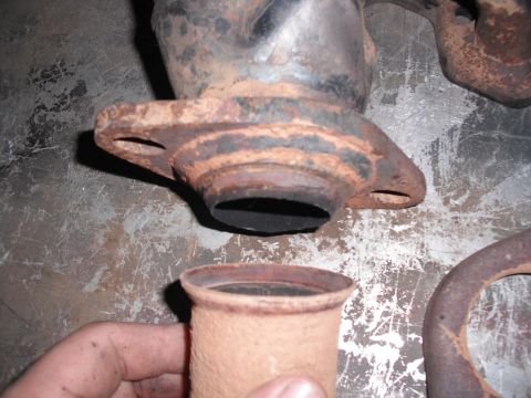 1991 Ford Bronco - Close-up of a rusty exhaust pipe flange and a separate pipe fitting, likely for a vehicle's exhaust system.