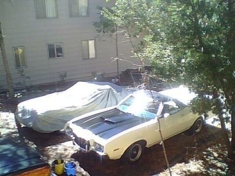 1972 Ford Ranchero - A cream 1972 Ford Ranchero with a black hood scoop is parked outside next to another covered vehicle.
