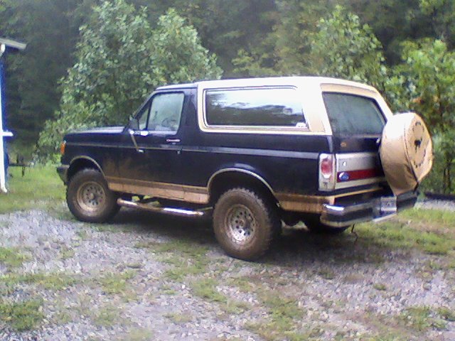 1989 Ford Bronco parked on gravel with trees in background