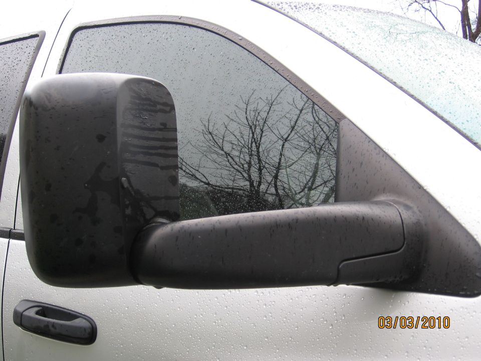 Black tow mirror on a white truck with water droplets