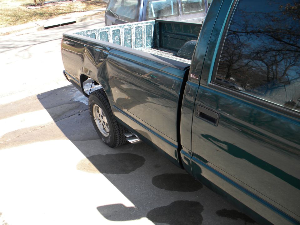 Green 1995 GMC Sierra 1500 pickup truck, dented rear fender, dual exhaust pipes, side view