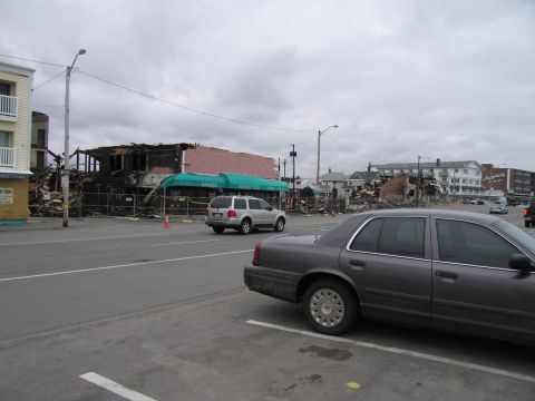 2001 Ford Crown Victoria - A dark gray 2001 Ford Crown Victoria is parked in a lot with a building fire in the background.