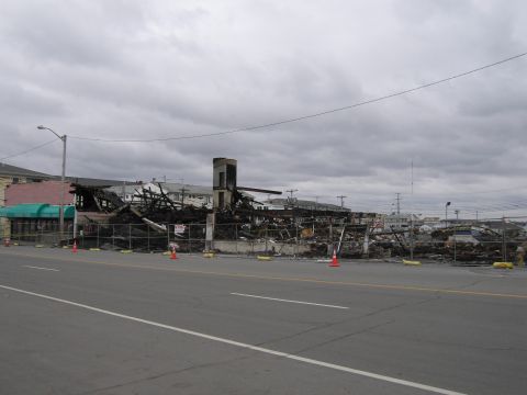 2001 Ford Crown Victoria - A building reduced to rubble and charred remains after a fire, cordoned off with fencing.