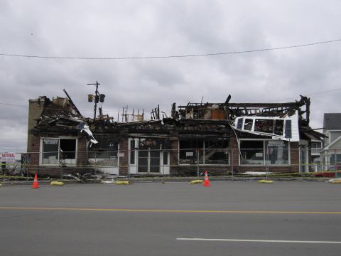 2001 Ford Crown Victoria - A building heavily damaged by fire, with debris and caution tape visible.