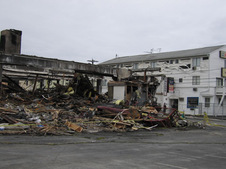 Debris from a fire in front of a damaged building with an 'Arcade Inn' sign
