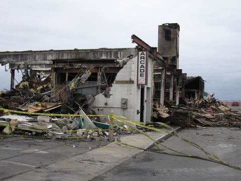 2001 Ford Crown Victoria - The aftermath of a fire has left an arcade building in ruins, with debris scattered across the scene.