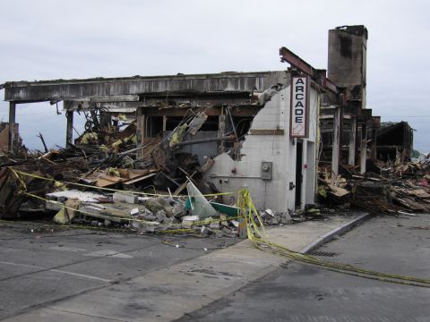 2001 Ford Crown Victoria - A building, identified by an "ARCADE" sign, is heavily damaged with debris scattered around the exterior.