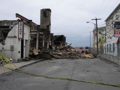 2001 Ford Crown Victoria - A street is filled with debris from fire-damaged buildings, with caution tape marking off the area.
