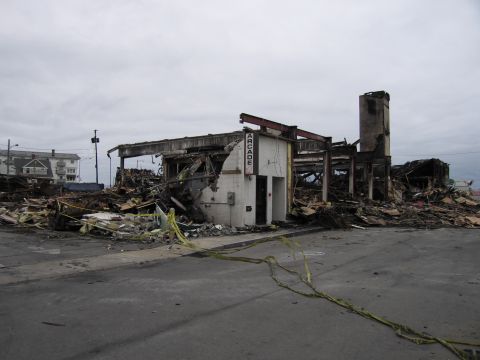 2001 Ford Crown Victoria - The aftermath of a fire shows a destroyed arcade building with extensive structural damage and debris scattered around.
