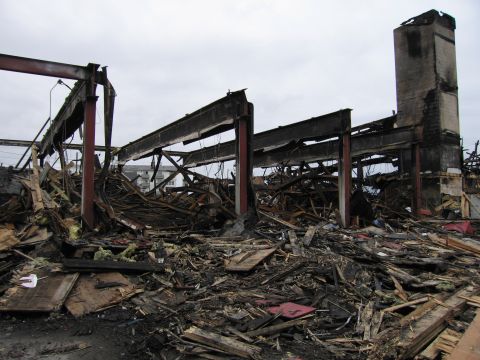 2001 Ford Crown Victoria - The scene shows the extensive damage and debris left behind after a significant fire, with the building's structure severely compromised.