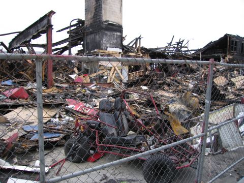 2001 Ford Crown Victoria - The scene shows the extensive damage and debris left behind after a fire, with a small go-kart partially visible.
