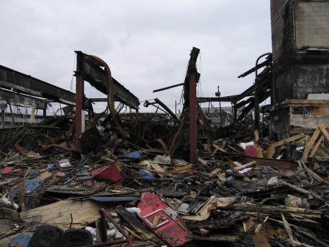 2001 Ford Crown Victoria - The aftermath of a fire shows a collapsed structure and a large pile of debris.