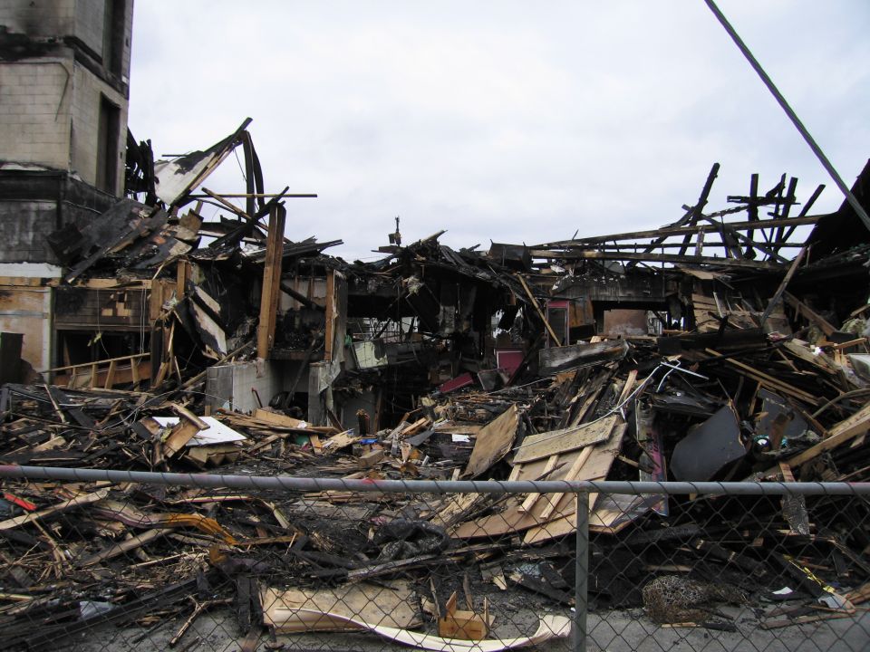 Building wreckage after a fire, with charred debris and collapsed structure