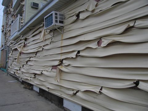 2001 Ford Crown Victoria - The siding on this building is severely damaged, with large sections peeling away.