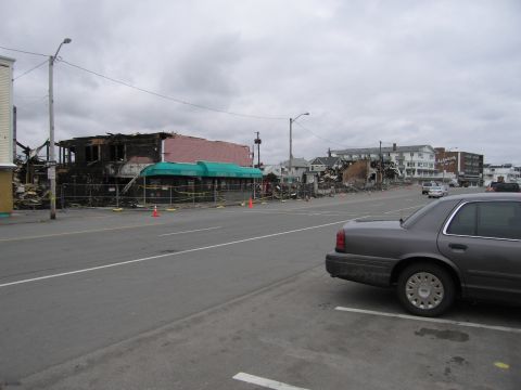 2001 Ford Crown Victoria - A sedan is parked in a lot with damaged buildings in the background under a cloudy sky.