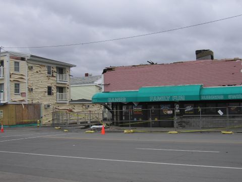 2001 Ford Crown Victoria - Buildings show significant damage from an apparent storm or disaster, with debris and caution tape visible.