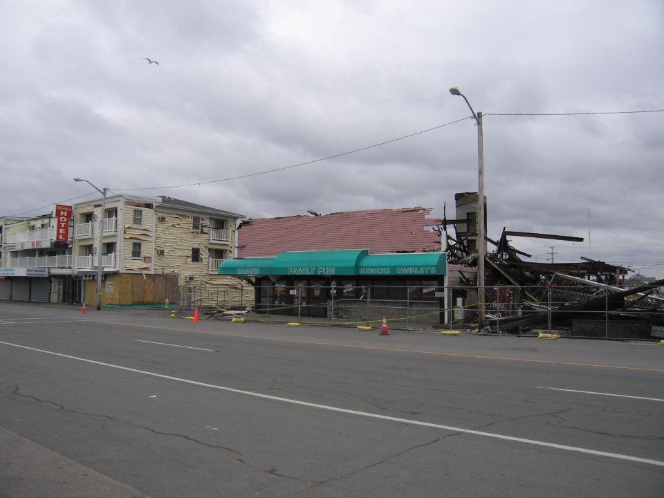 Buildings damaged by fire, one with a green awning that says 'Family Fun'. A hotel is visible to the left