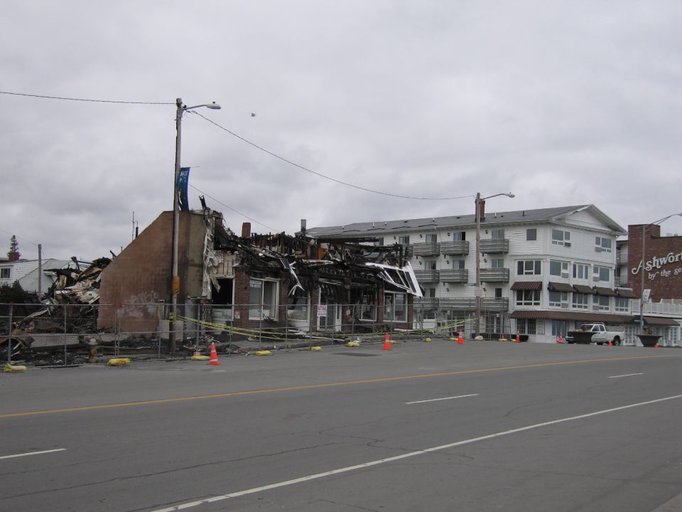 White pickup truck parked near a fire-damaged building and a multi-story hotel