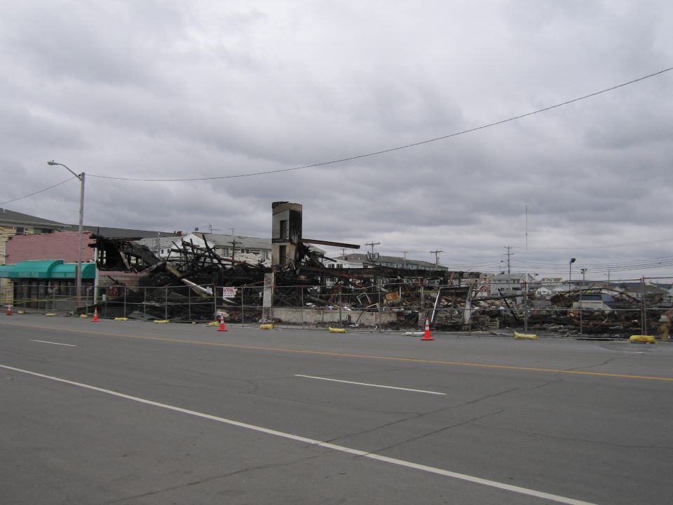 Building reduced to rubble and charred wood after a fire. Fencing surrounds the debris