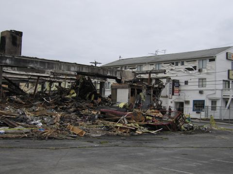 2001 Ford Crown Victoria - The scene shows the extensive damage and debris left behind after a fire, with a motel building standing nearby.