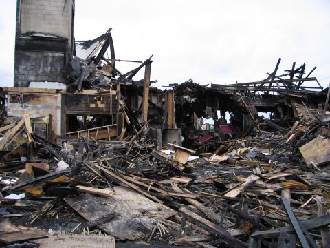2001 Ford Crown Victoria - The scene shows the extensive damage and destruction caused by a building fire, with debris covering the ground.