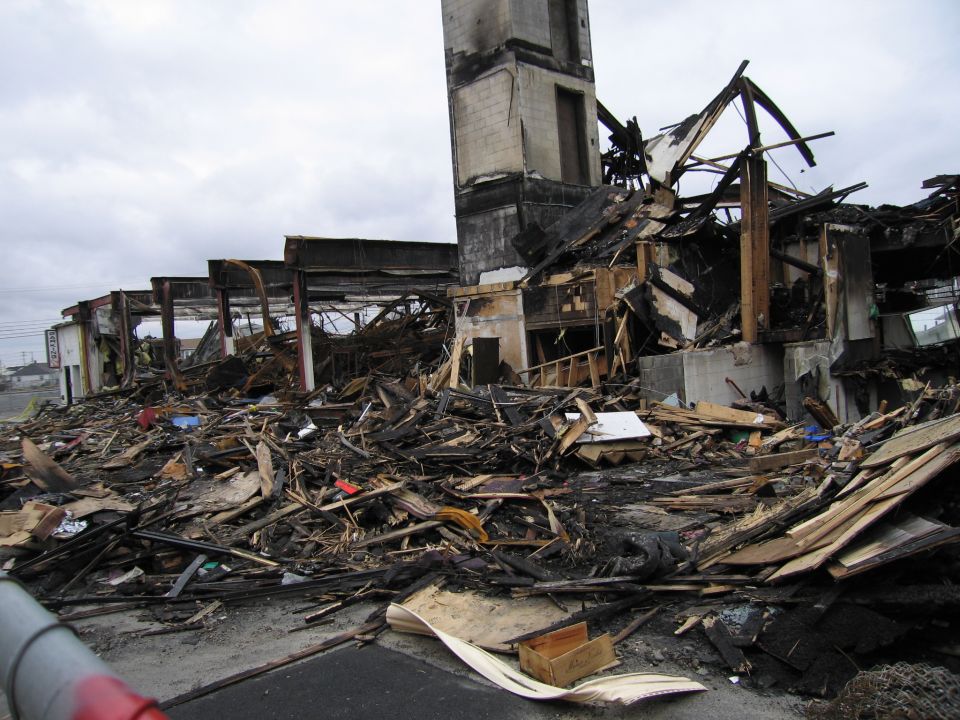 aftermath of a fire, showing a collapsed building with debris everywhere