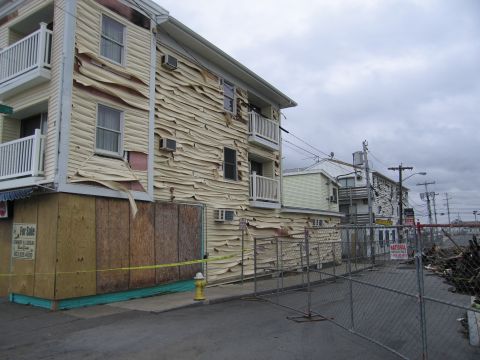 2001 Ford Crown Victoria - Buildings show significant damage with peeling siding and boarded windows after an event.