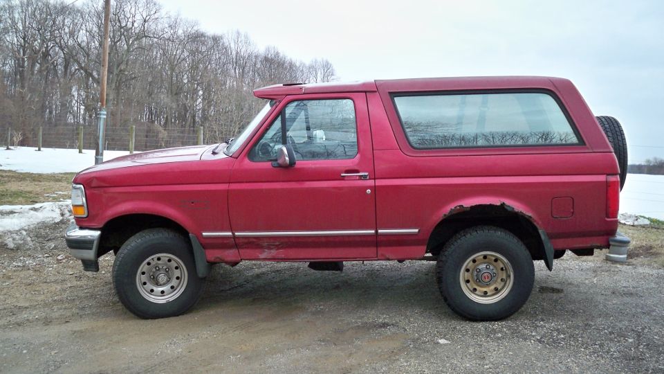 Red full-size two-door SUV parked on dirt in a snowy field