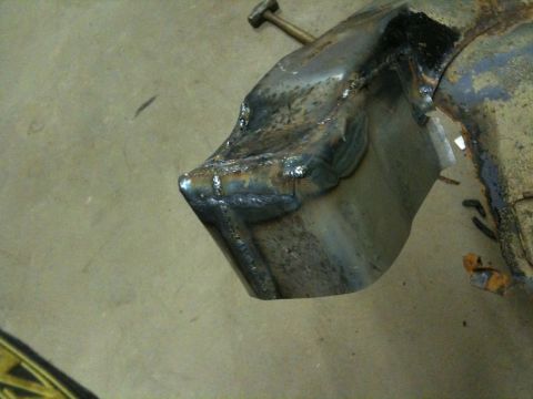 1993 Ford Bronco - A close-up view of a heavily repaired and rusted metal component, likely from a vehicle's undercarriage.