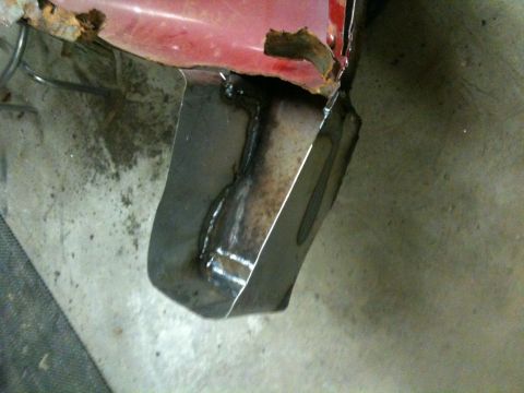1993 Ford Bronco - Close-up of a rusted red fender with a newly welded metal patch on the lower section.