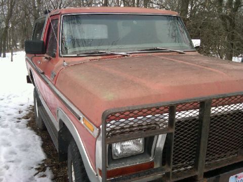 1987 Ford Bronco - Front view of a red Ford Bronco with a custom grille guard, parked outdoors in a snowy environment.