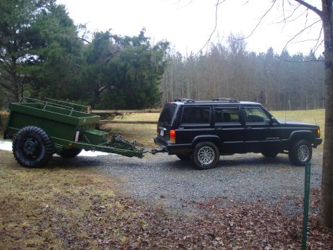 1995 Ford Bronco - A black Jeep Cherokee tows a green utility trailer through a wooded area.