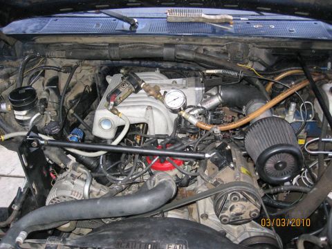 1994 Ford Bronco - Close-up view of a modified engine bay, showing various aftermarket parts and a pressure gauge.