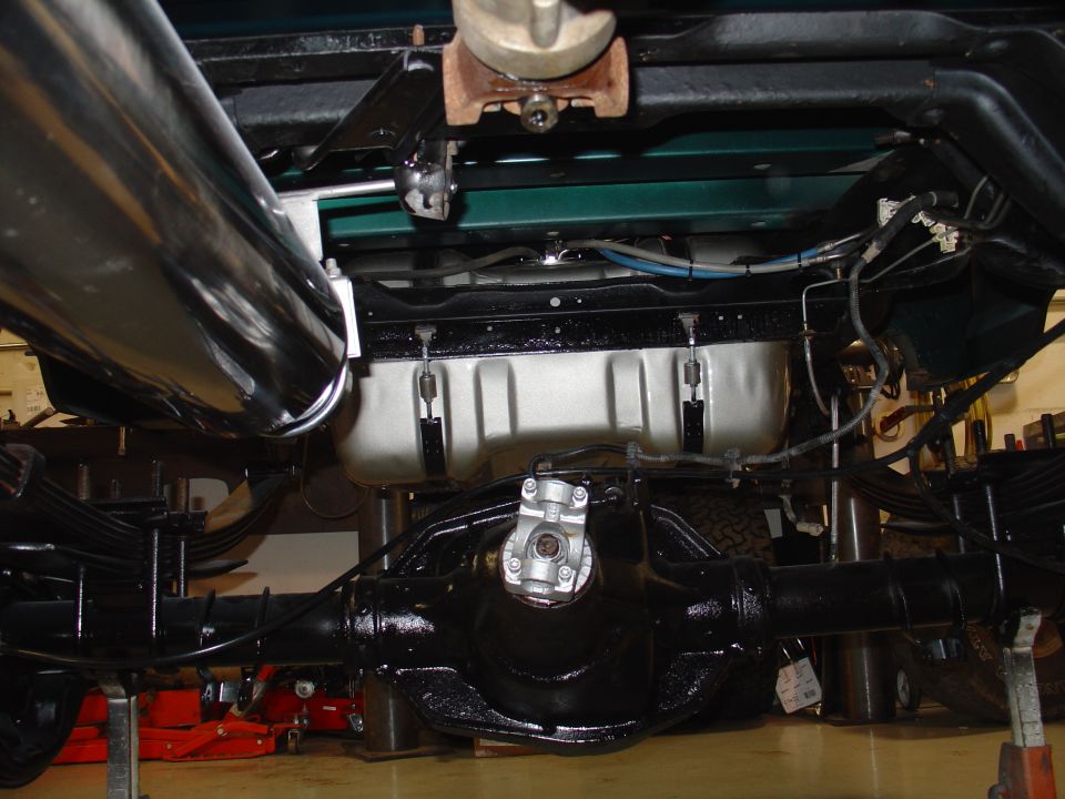 Underside view of a truck's rear axle, driveshaft, and exhaust system. The vehicle appears to be on a lift
