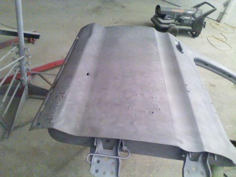 1979 Ford F-250 - A bare metal car hood is prepared for repair in a workshop setting.