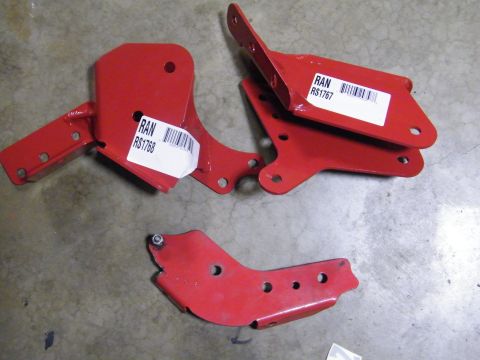 1982 Ford Bronco - A collection of red metal brackets, possibly for vehicle modification, are laid out on a concrete surface.