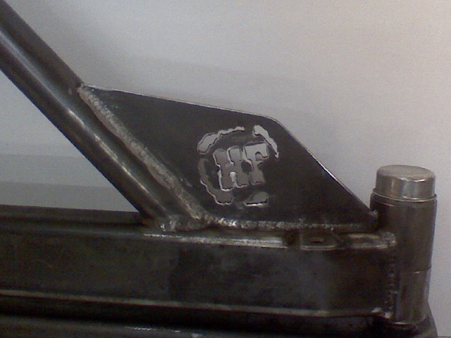 Metal bracket with cut-out logo, possibly "HF". Welded construction