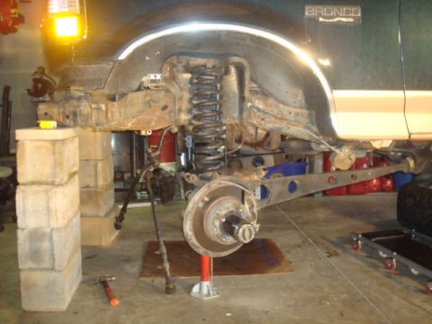 1995 Ford Bronco - The front suspension of a green Ford Bronco is disassembled and supported in a garage setting.