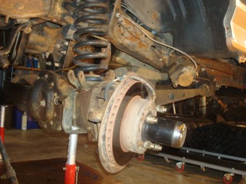 1995 Ford Bronco - Close-up view of the front axle and suspension components of a vehicle undergoing repair.